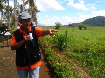 Tita Brenie shows ATM members RT Mining’s operations in Maya village. One of its facilities is in the far background.